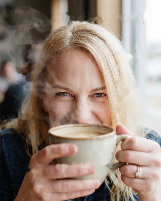 Stephanie, founder of Dropvine, smiling over a cup of coffee